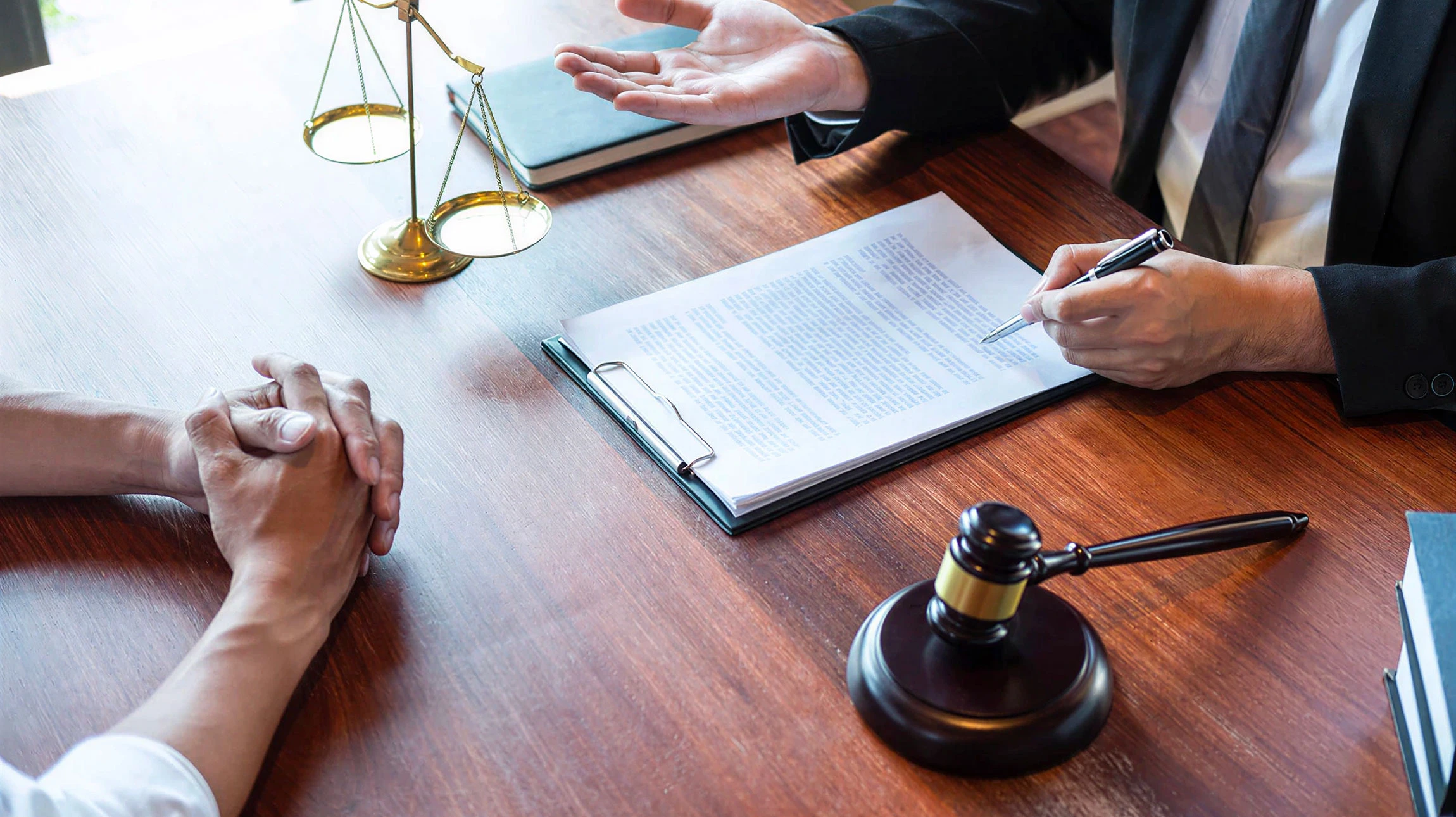 Bureau juridique avec marteau de juge posé sur livre de droit ouvert, entouré de piles de codes et ouvrages juridiques